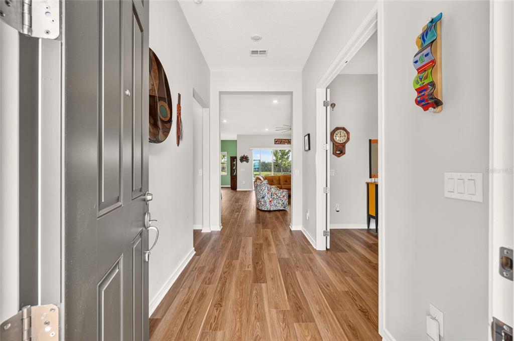 An entryway with wood-look flooring leads into a living area with a view of the outdoors — 5235 SW 88TH CIRCLE, OCALA, FL