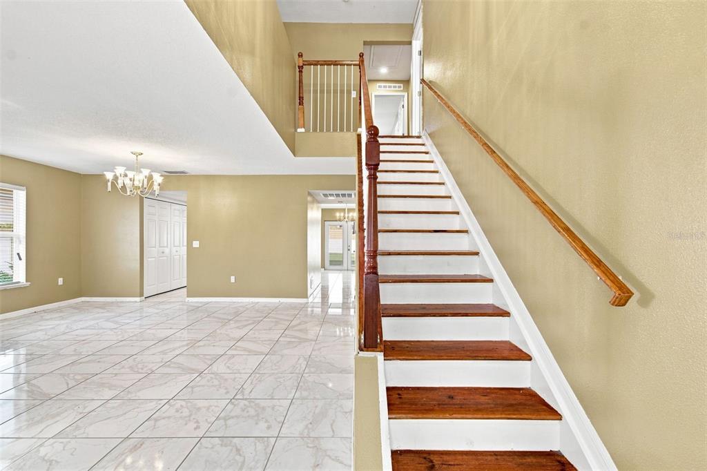 An interior view shows a tiled foyer with a staircase leading to an upper landing — 5155 SPANISH OAKS DRIVE, LAKELAND, FL