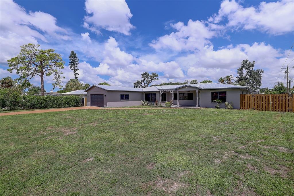 A single-story house with a brown garage door and a concrete driveway under a blue sky — 323 SUWANEE AVENUE, SARASOTA, FL