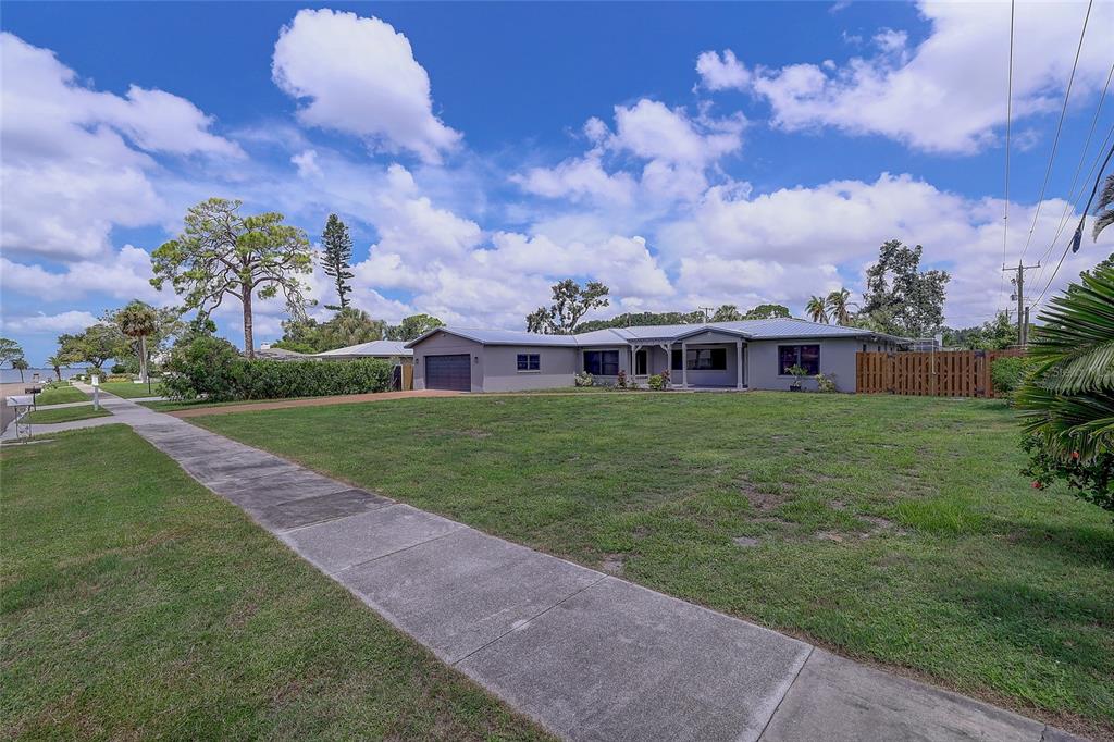 An open-concept living area features wood-look tile flooring, a kitchen with white cabinets, and glass doors — 323 SUWANEE AVENUE, SARASOTA, FL