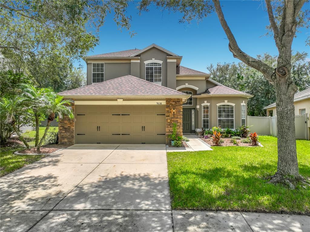 A two-story suburban house with a stone-accented garage and a front lawn — 9038 VICKROY TERRACE, OVIEDO, FL