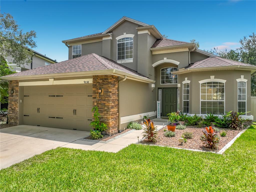 A two-story house with a stone-accented garage, a brown roof, and a landscaped front yard — 9038 VICKROY TERRACE, OVIEDO, FL