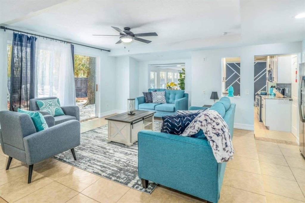 A living room with blue furniture, a patterned area rug, and a sliding glass door — 2917 STETSON STREET, MELBOURNE, FL