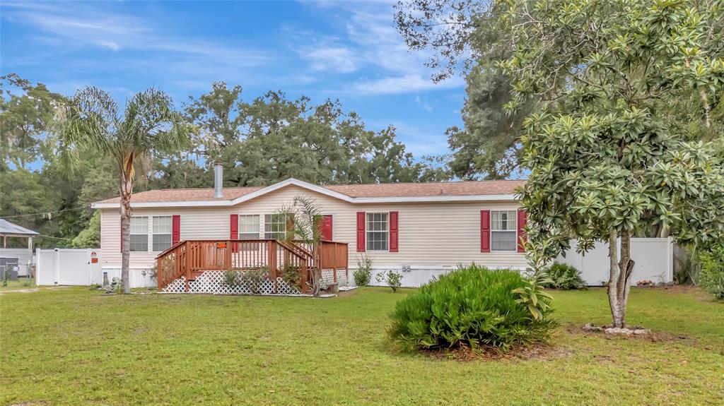 A wooden deck with stairs leads to the front entrance of a beige mobile home — 2716 SEMINOLE TRAIL, LEESBURG, FL
