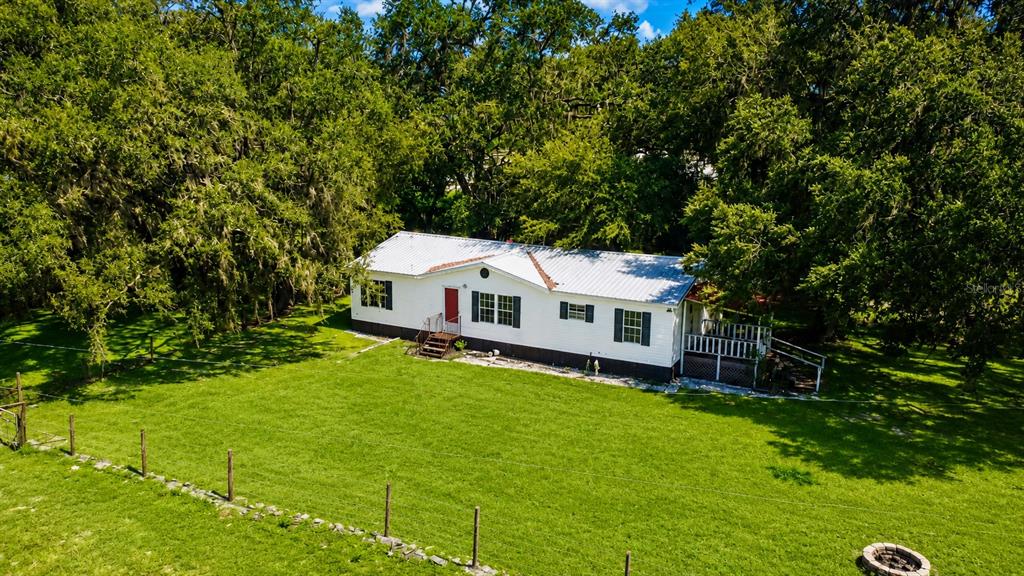 An aerial view shows a white manufactured home with a metal roof surrounded by trees — 14240 SR 471, WEBSTER, FL