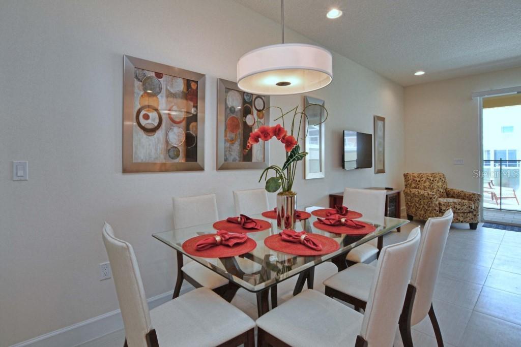 A dining room features a glass-topped table, six upholstered chairs, and abstract wall art — 1523 STILL DRIVE, CLERMONT, FL