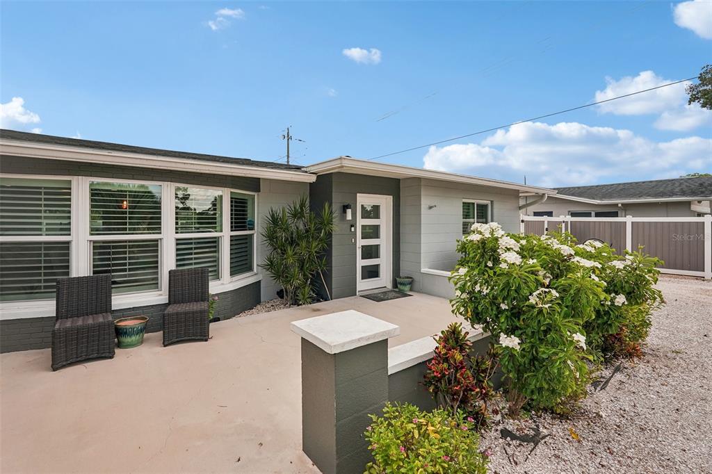 A gray house exterior features a front patio with two chairs and a white door — 365 SHAMROCK BOULEVARD, VENICE, FL