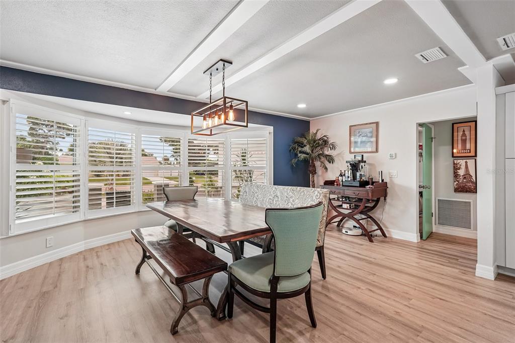A dining room features a wooden table, a bench, chairs, and a bay window — 365 SHAMROCK BOULEVARD, VENICE, FL