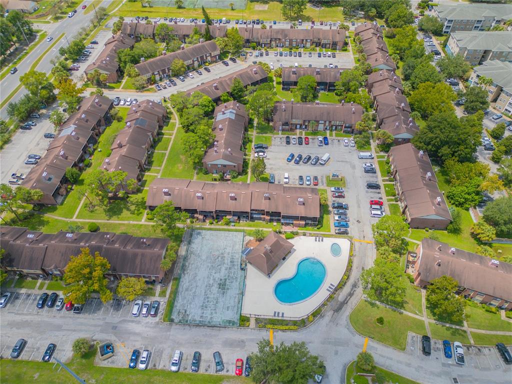 An aerial view shows a residential apartment complex with a swimming pool and tennis court — 5038 DOWNING STREET UNIT 7, ORLANDO, FL