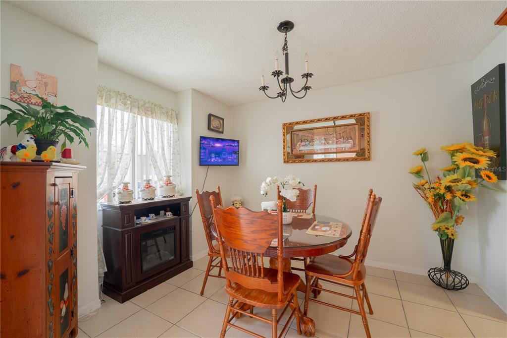 A dining room features a round wooden table, chairs, a chandelier, and tile flooring — 5038 DOWNING STREET UNIT 7, ORLANDO, FL