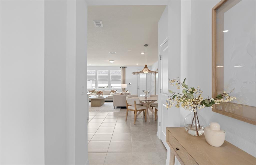 A view from a hallway looking into a bright, open-concept living and dining area — 6909 CREEK FALLS ALLEY, CLERMONT, FL