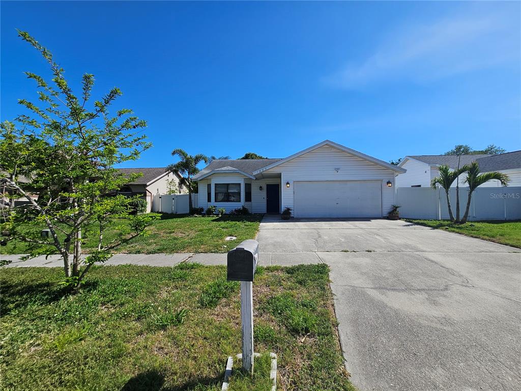 A single-story house with white siding, a two-car garage, and a front lawn — 1885 FEATHER TREE CIRCLE, CLEARWATER, FL
