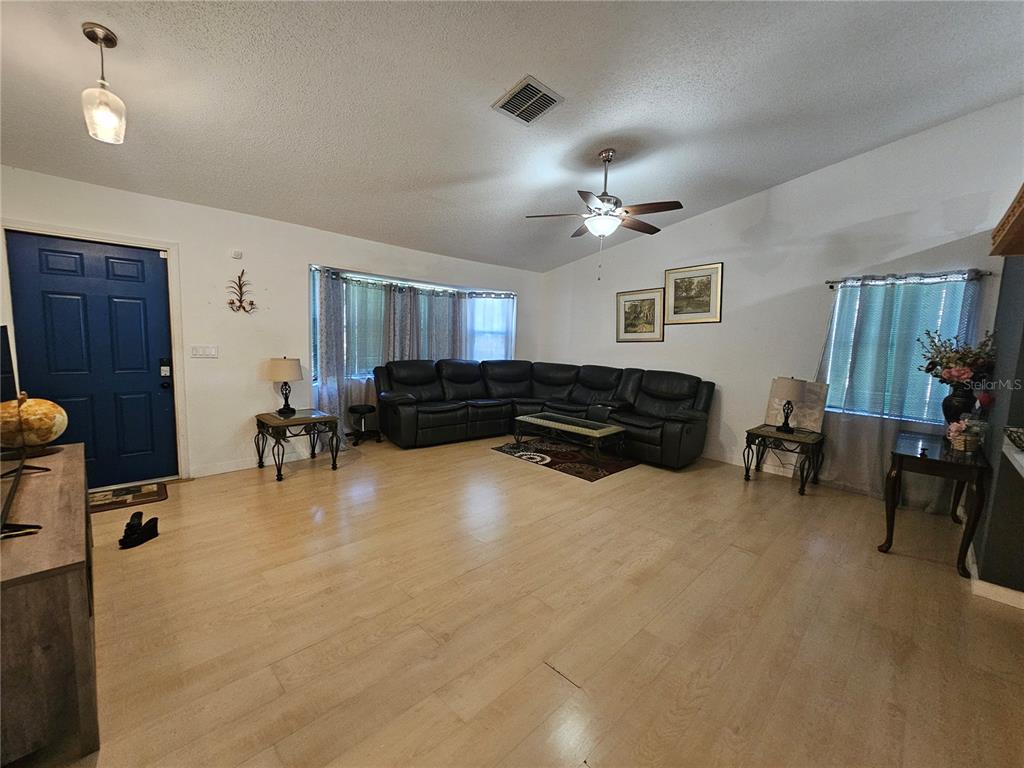 A living room features light wood flooring, a dark sectional sofa, and a blue door — 1885 FEATHER TREE CIRCLE, CLEARWATER, FL