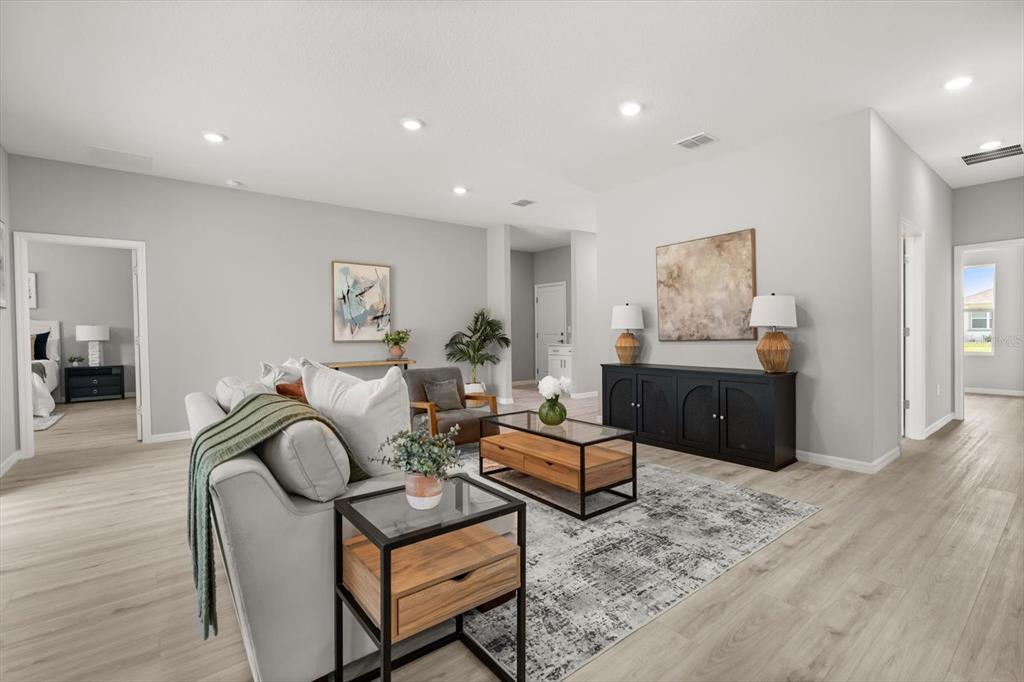 A living room features light wood-look flooring, a gray sofa, and a black console table — 6754 COCONUT GROVE DRIVE, SEBRING, FL