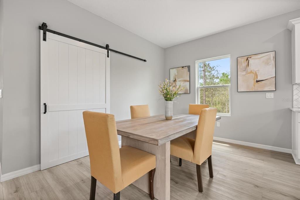 A dining room features a wooden table, four yellow chairs, and a white barn door — 6754 COCONUT GROVE DRIVE, SEBRING, FL