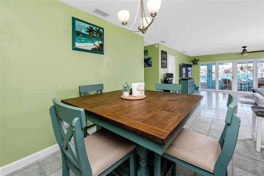 A dining area features a square wooden table with teal chairs against light green walls — 11215 3RD STREET E, TREASURE ISLAND, FL
