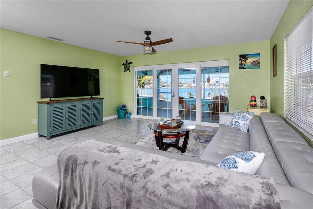 A living room with light green walls, a grey sectional sofa, and sliding glass doors — 11215 3RD STREET E, TREASURE ISLAND, FL