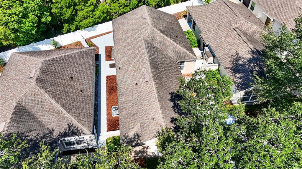 An aerial view shows the shingled roofs of three adjacent houses with a narrow walkway between — 4224 SNOWDON STREET, CLERMONT, FL