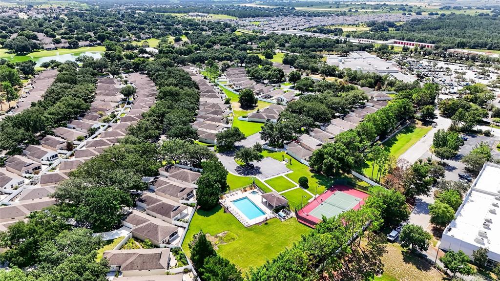 An aerial view shows a residential neighborhood with a swimming pool, tennis court, and houses — 4224 SNOWDON STREET, CLERMONT, FL
