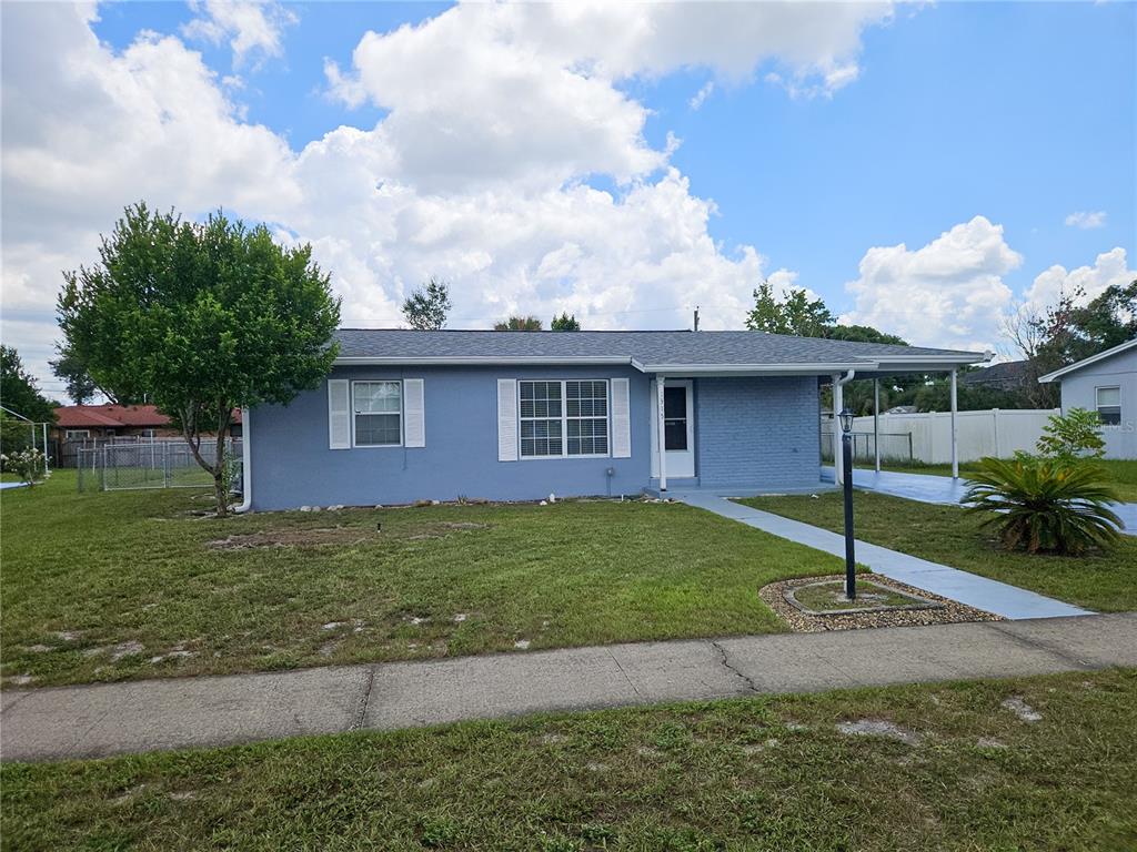 A single-story blue house with a carport, white shutters, and a front lawn — 1315 E HANCOCK DRIVE, DELTONA, FL