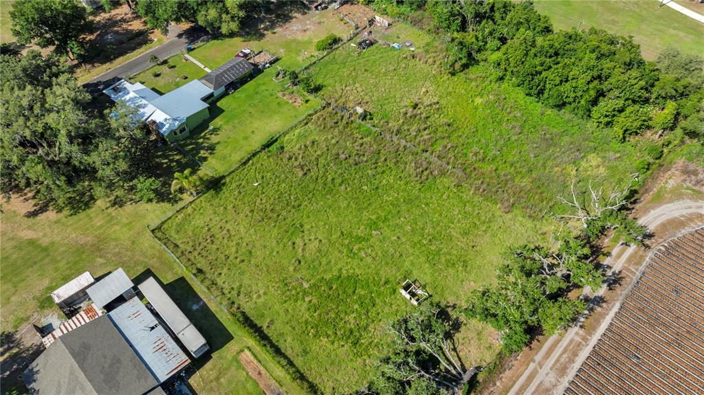 An aerial view shows a large, grassy rectangular lot bordered by trees and neighboring houses — 13610 ACKER ROAD, DOVER, FL
