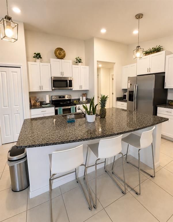 A kitchen features white cabinets, granite countertops, a central island with bar seating, and appliances — 9950 BRANCHING SHIP TRACE, WESLEY CHAPEL, FL