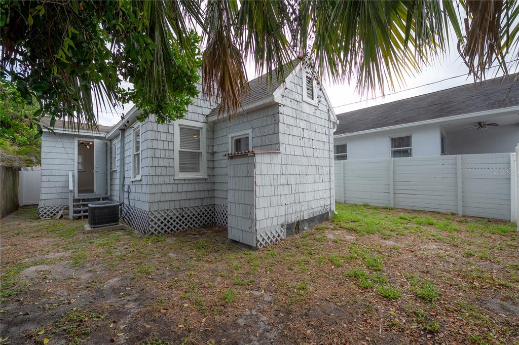 The exterior of a house features gray shingle siding, a blue front door, and windows — 405 E CAYUGA STREET, TAMPA, FL