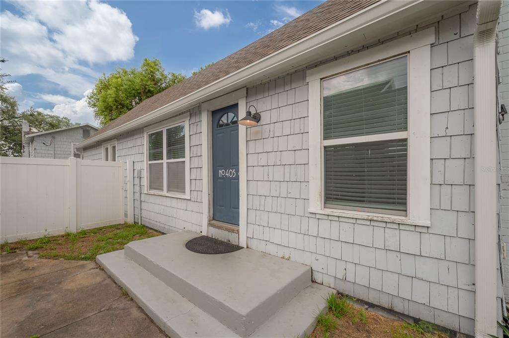 A view through an open blue door into a kitchen with white cabinets and flooring — 405 E CAYUGA STREET, TAMPA, FL