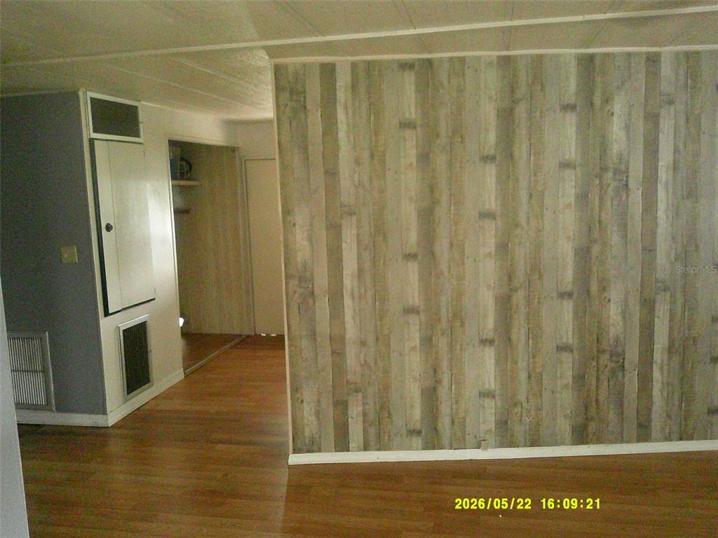 A room features wood-look plank flooring and a wall covered in vertical wood-grain paneling — 15211 SE 104TH COURT, SUMMERFIELD, FL