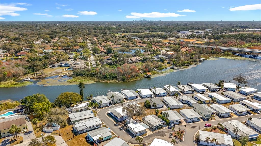 An aerial view shows a mobile home community situated along a river near a bridge — 10101 N LAKE DRIVE UNIT 89, LARGO, FL