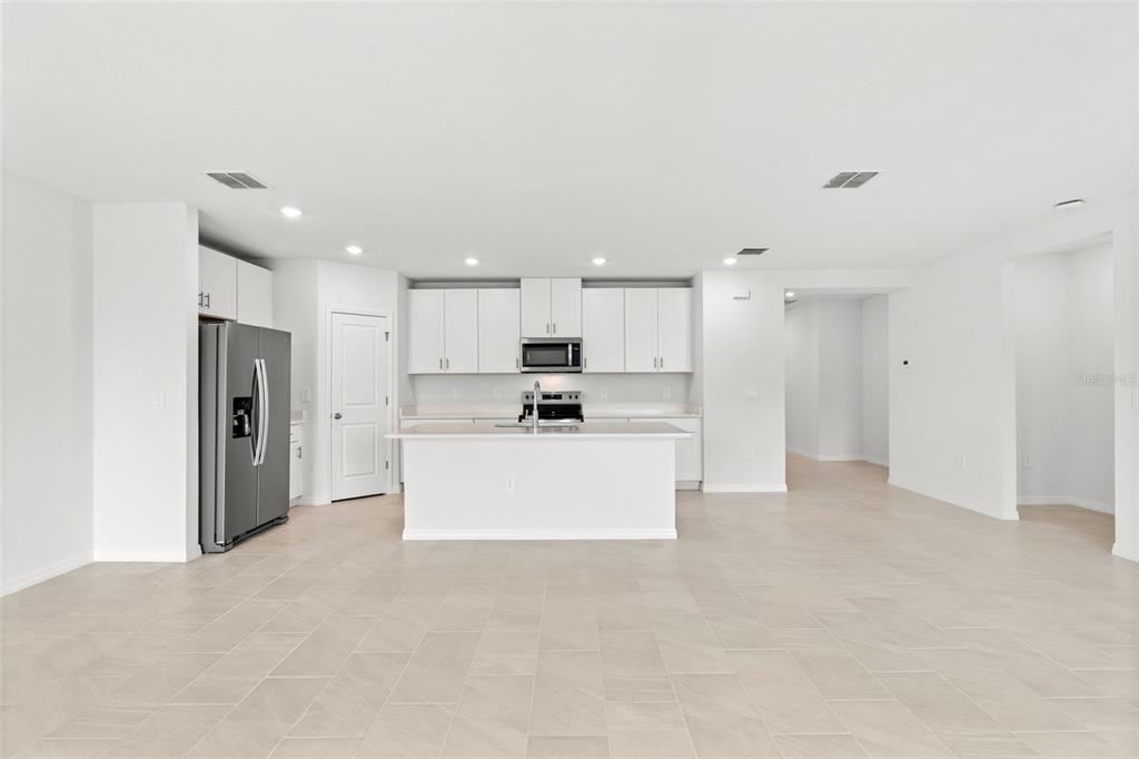 A modern kitchen features white cabinets, stainless steel appliances, a central island, and tiled flooring — 112 OUTBACK HIDEAWAY AVENUE, NOKOMIS, FL