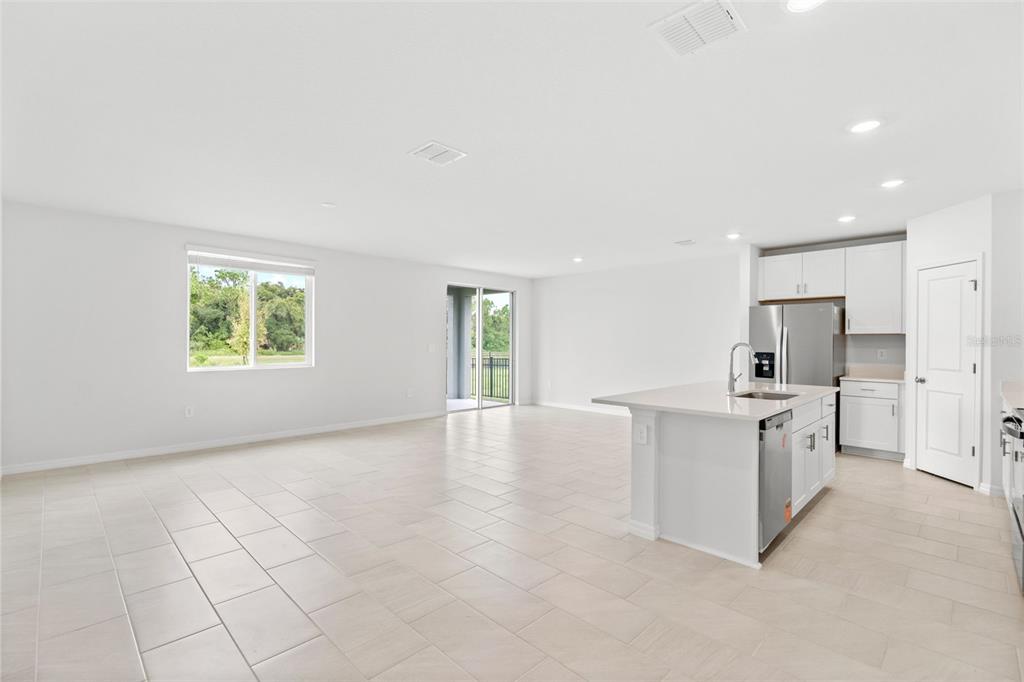 A bright open-concept kitchen and living area featuring white cabinetry, an island, and tile flooring — 112 OUTBACK HIDEAWAY AVENUE, NOKOMIS, FL