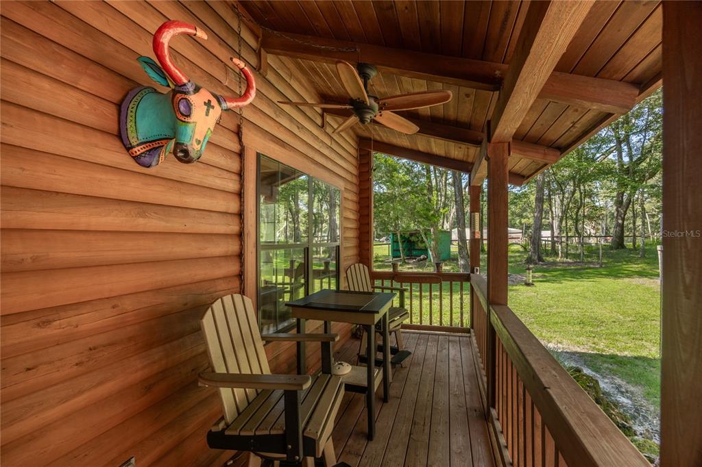 A wooden porch features a decorative bull head, a small table, and two chairs — 16350 NE 53RD LANE, WILLISTON, FL