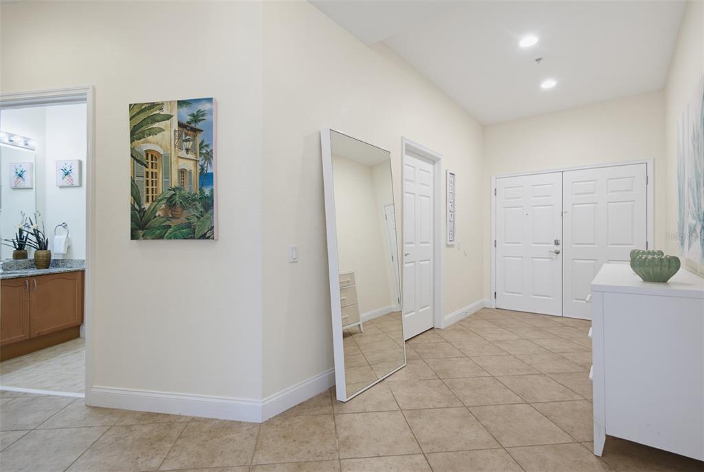 An entryway features tile flooring, a large floor mirror, a white console table, and doors — 2 OCEANS WEST BOULEVARD UNIT 103, DAYTONA BEACH SHORES, FL
