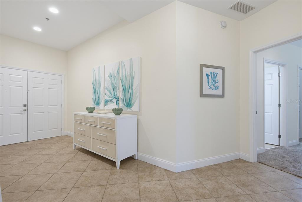 A tiled entryway features a white dresser, wall art, and a doorway leading to another room — 2 OCEANS WEST BOULEVARD UNIT 103, DAYTONA BEACH SHORES, FL