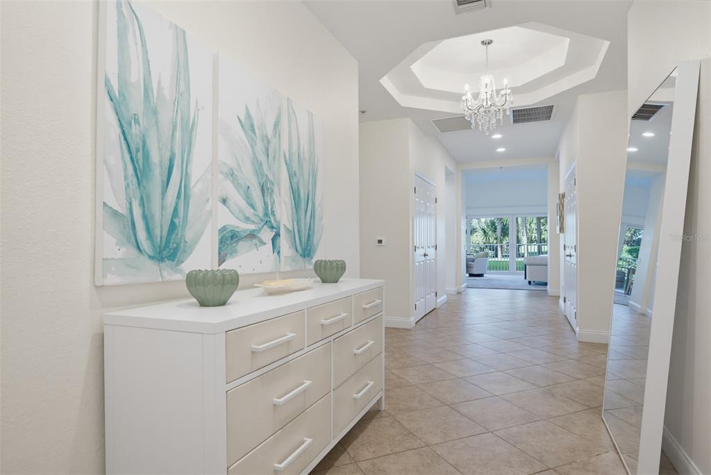A bright entryway features a white dresser, wall art, a chandelier, and a floor mirror — 2 OCEANS WEST BOULEVARD UNIT 103, DAYTONA BEACH SHORES, FL