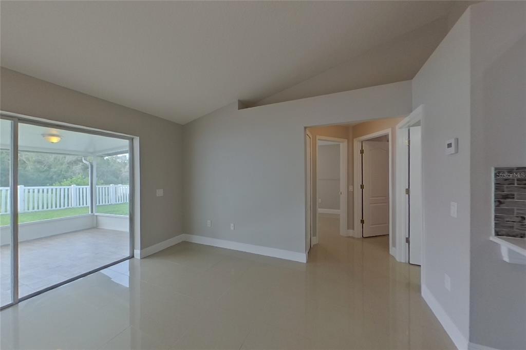 A room with light gray walls, tile flooring, a vaulted ceiling, and a sliding glass door — 30746 BIRDHOUSE DRIVE, WESLEY CHAPEL, FL