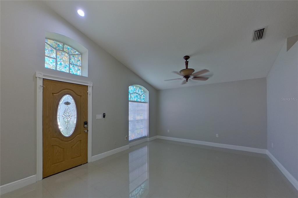 An empty room with light tile floors, a ceiling fan, and arched stained-glass windows — 30746 BIRDHOUSE DRIVE, WESLEY CHAPEL, FL