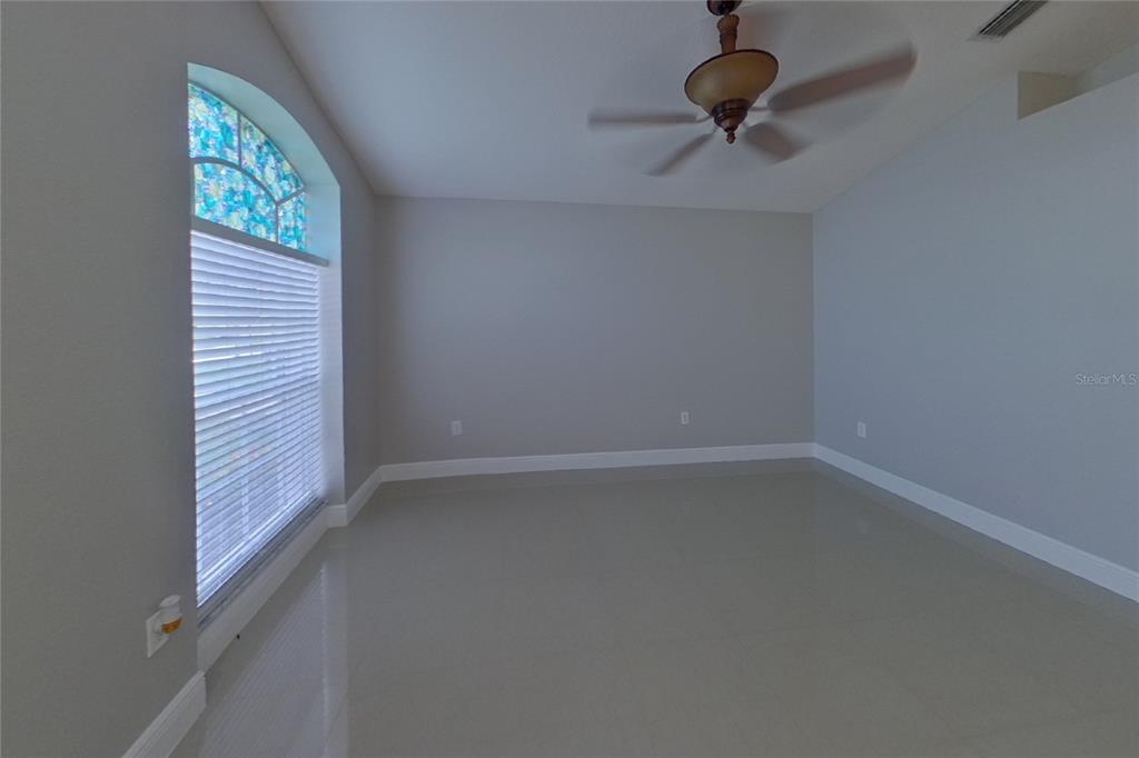An empty room features light gray walls, tile flooring, a ceiling fan, and an arched window — 30746 BIRDHOUSE DRIVE, WESLEY CHAPEL, FL