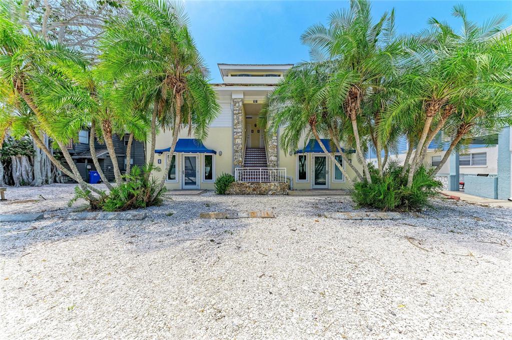 A two-story building with palm trees and a shell-covered parking area in front — 101 PALM AVENUE UNIT 3, ANNA MARIA, FL
