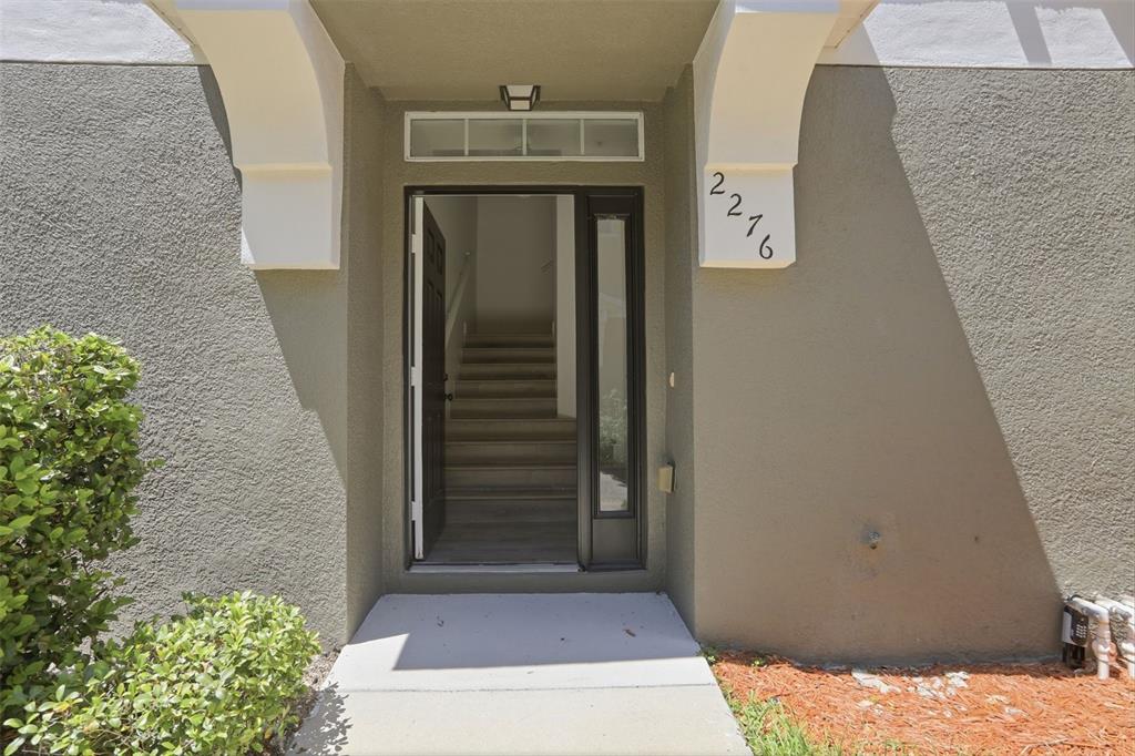 The front entrance of a home features a concrete walkway, a staircase, and house number 2216 — 2276 BETSY ROSS LANE UNIT A, ST CLOUD, FL