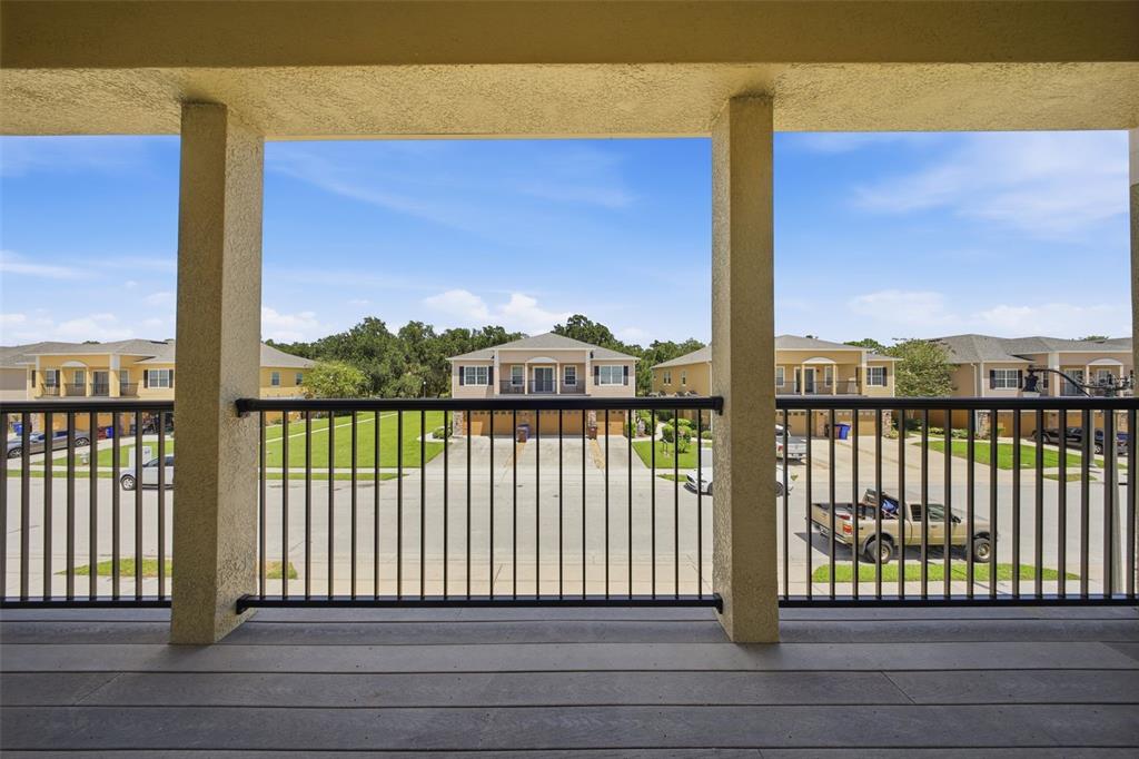 A covered balcony with a dark metal railing overlooks a suburban street and residential buildings — 2276 BETSY ROSS LANE UNIT A, ST CLOUD, FL