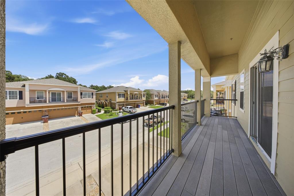 A covered balcony with gray decking and black metal railings overlooks a suburban street — 2276 BETSY ROSS LANE UNIT A, ST CLOUD, FL