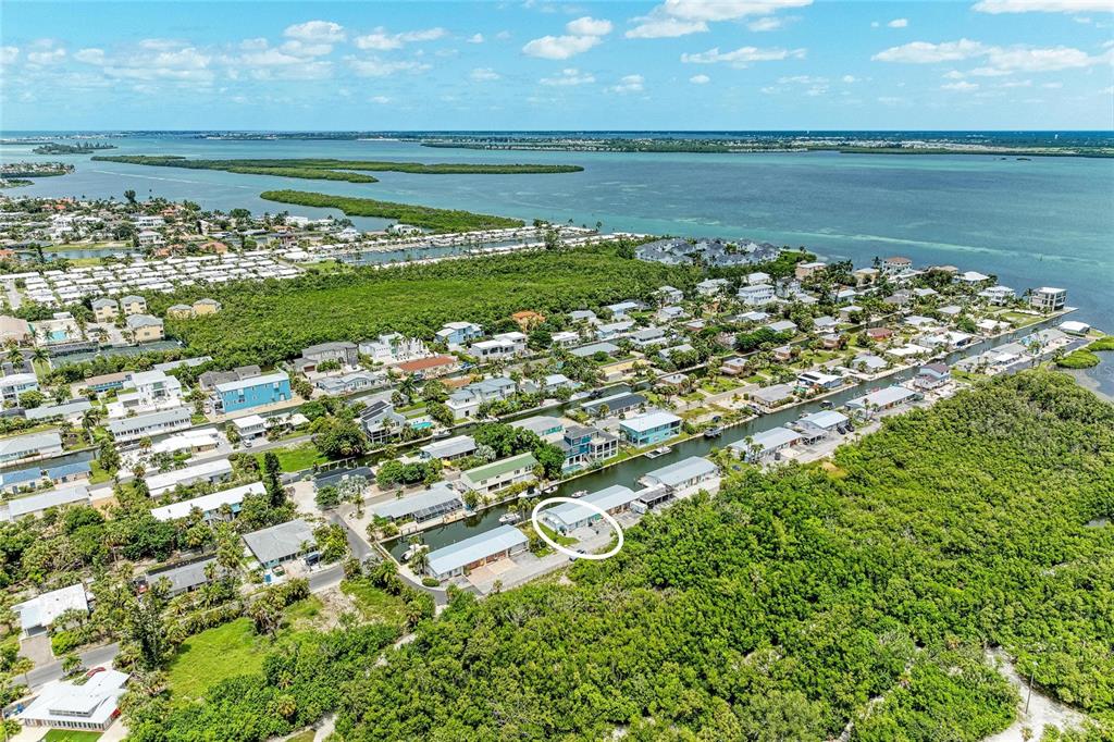 An aerial view shows a coastal neighborhood with houses situated along a canal — 707 SAINT JUDES DRIVE S UNIT 1, LONGBOAT KEY, FL