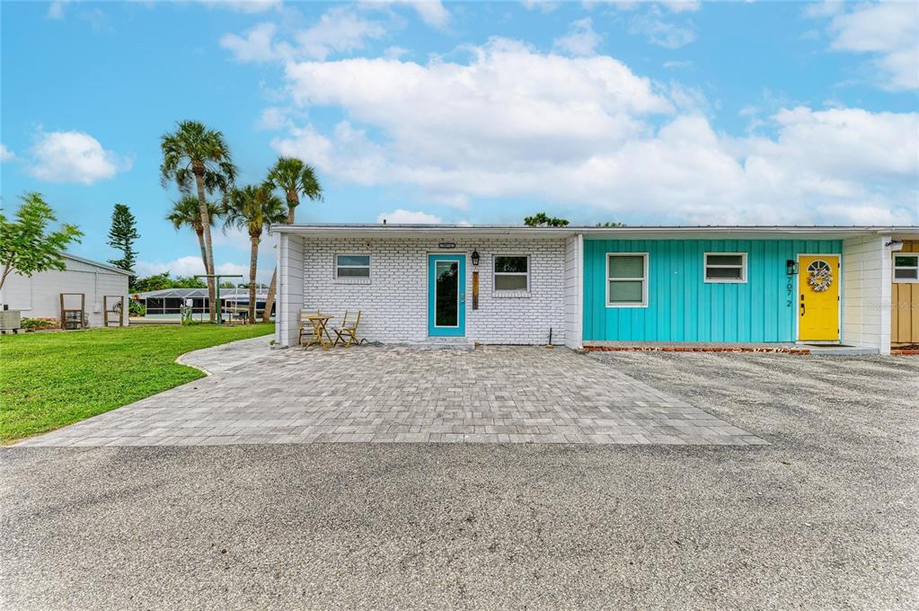 A single-story building with a white brick facade, turquoise siding, and a paved driveway — 707 SAINT JUDES DRIVE S UNIT 1, LONGBOAT KEY, FL