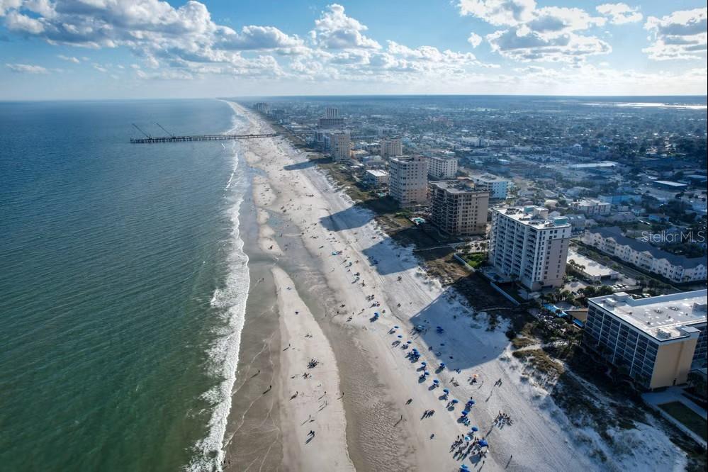 An aerial view shows a sandy beach, ocean waves, a fishing pier, and coastal high-rises — 6 BEACH WAY, JACKSONVILLE BEACH, FL