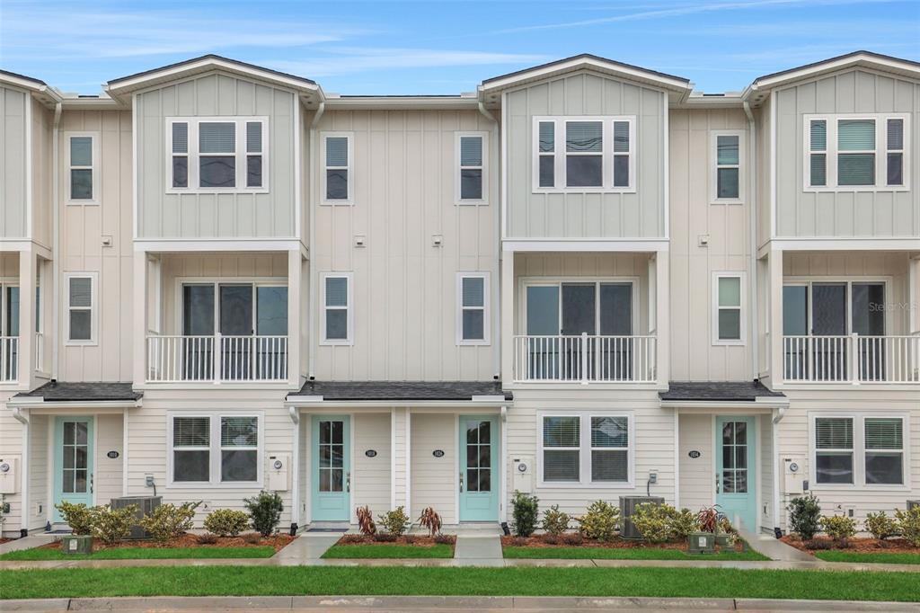 A row of three-story townhouses with light-colored siding, balconies, and light blue front doors — 6 BEACH WAY, JACKSONVILLE BEACH, FL