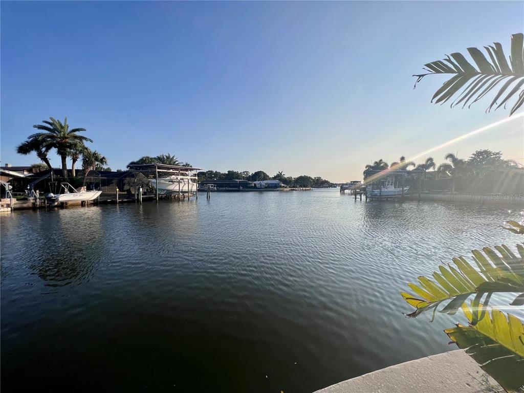 A view of a calm canal lined with docks, boats, and palm trees under a sky — 1796 BROOKSIDE BOULEVARD, LARGO, FL