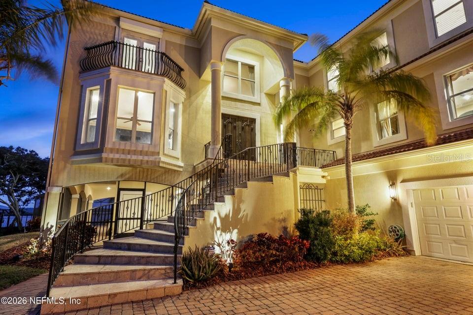 A multi-story house exterior features a curved stone staircase leading to an arched front entrance — 7149 MIDDLETON AVENUE, ST AUGUSTINE, FL