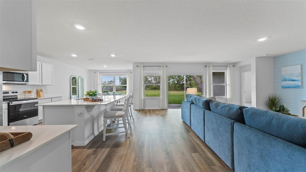 An open-concept kitchen and living area features white cabinetry, a large island, and blue seating — 3198 GREY MOSS DRIVE, ST CLOUD, FL